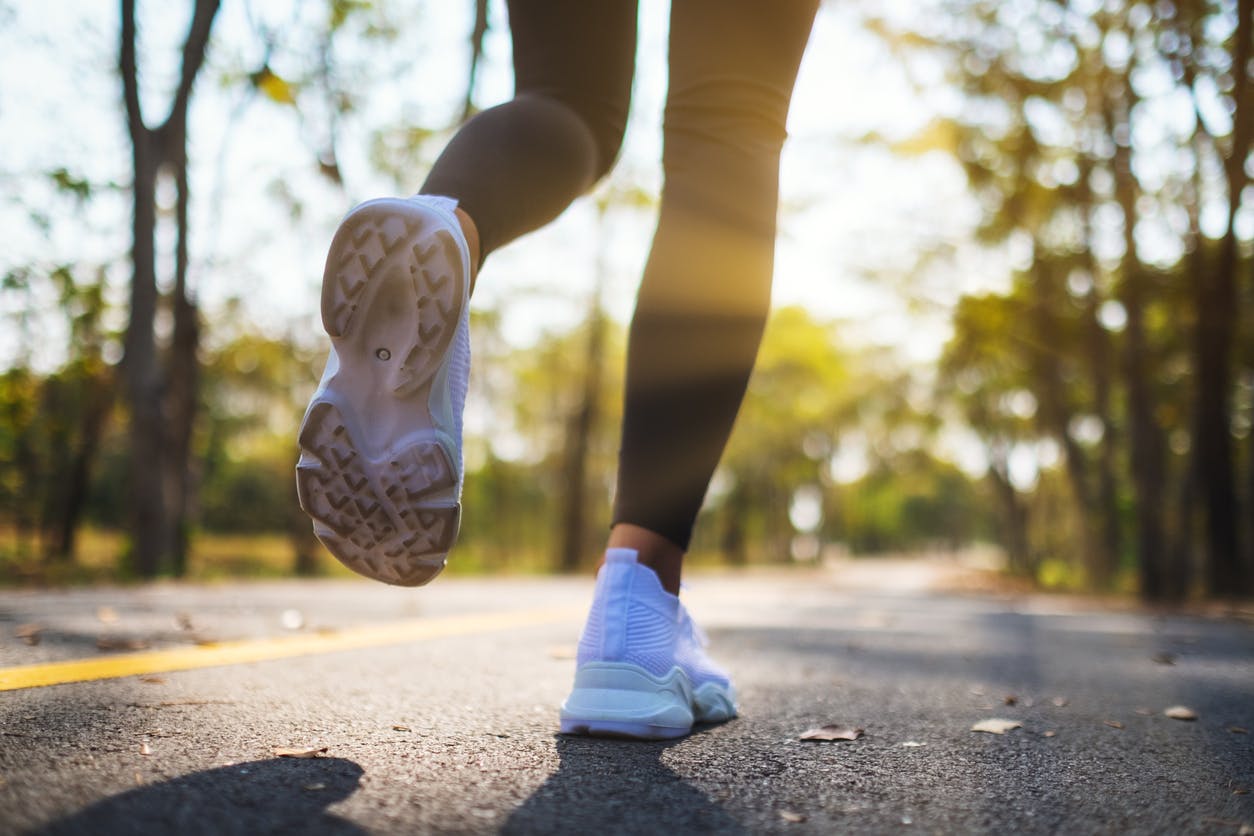 legs in leggings walking on a tree covered road. Chronic ankle pain,