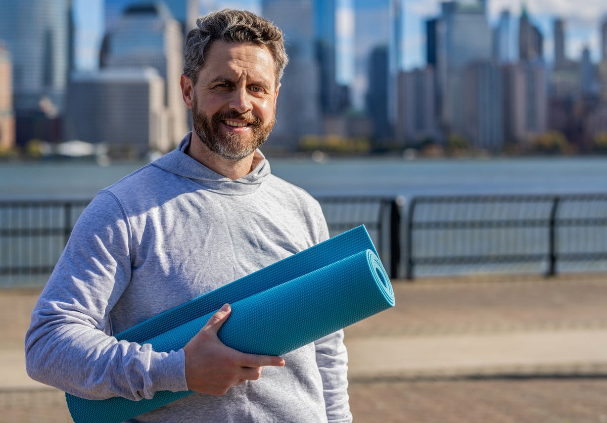 Man holding a rolled up yoga mat, in New York City