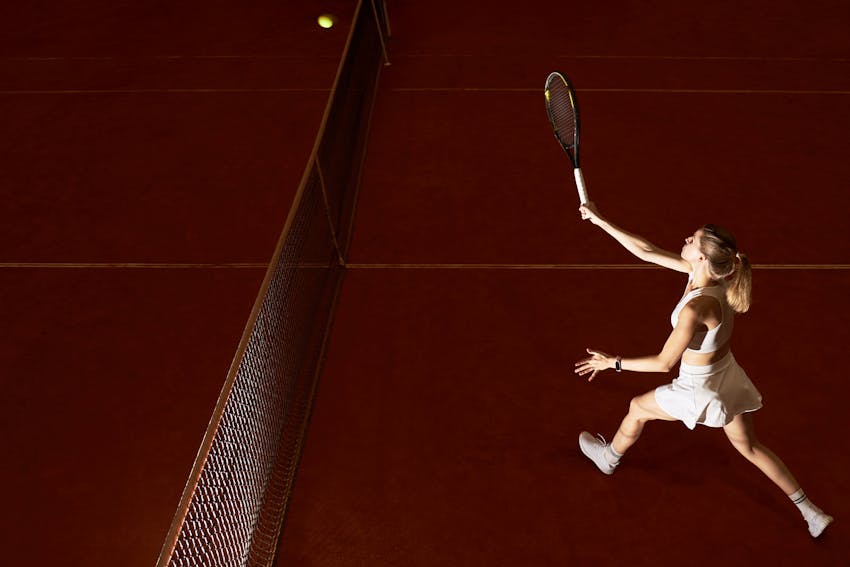 woman playing tenning on a brown court