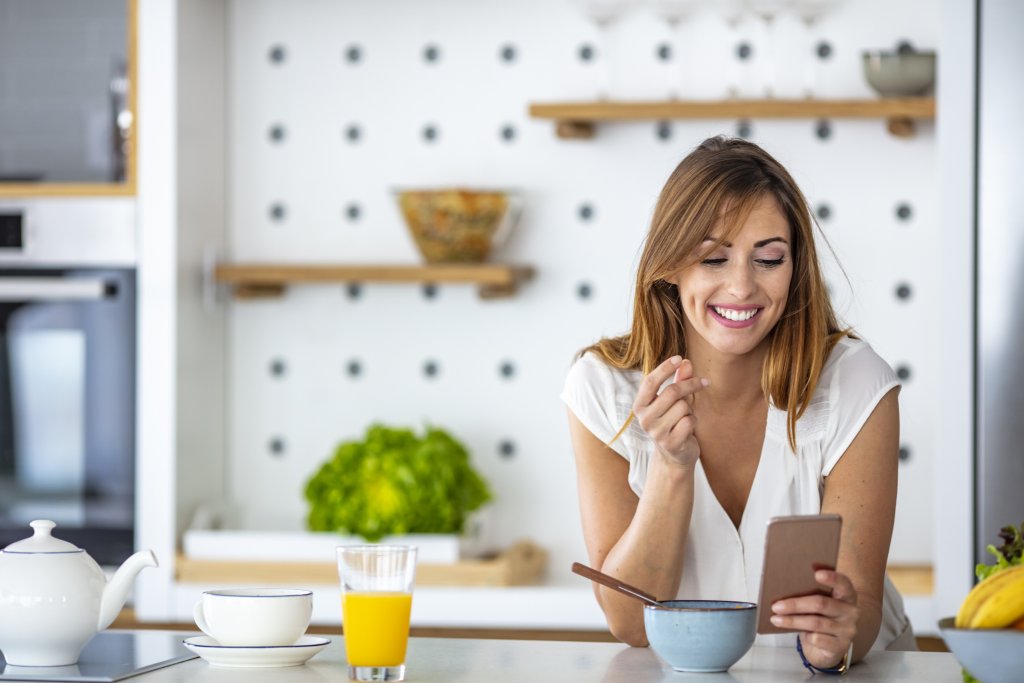Orientação nutricional - foto de uma mulher comendo e mexendo no celular