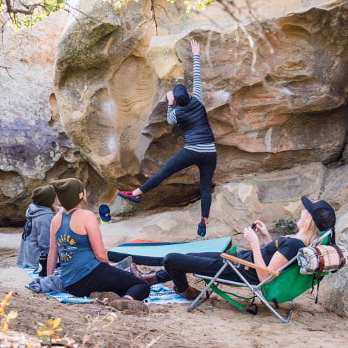 Image of three people in Yellow Belly merch watching someone climb a wall