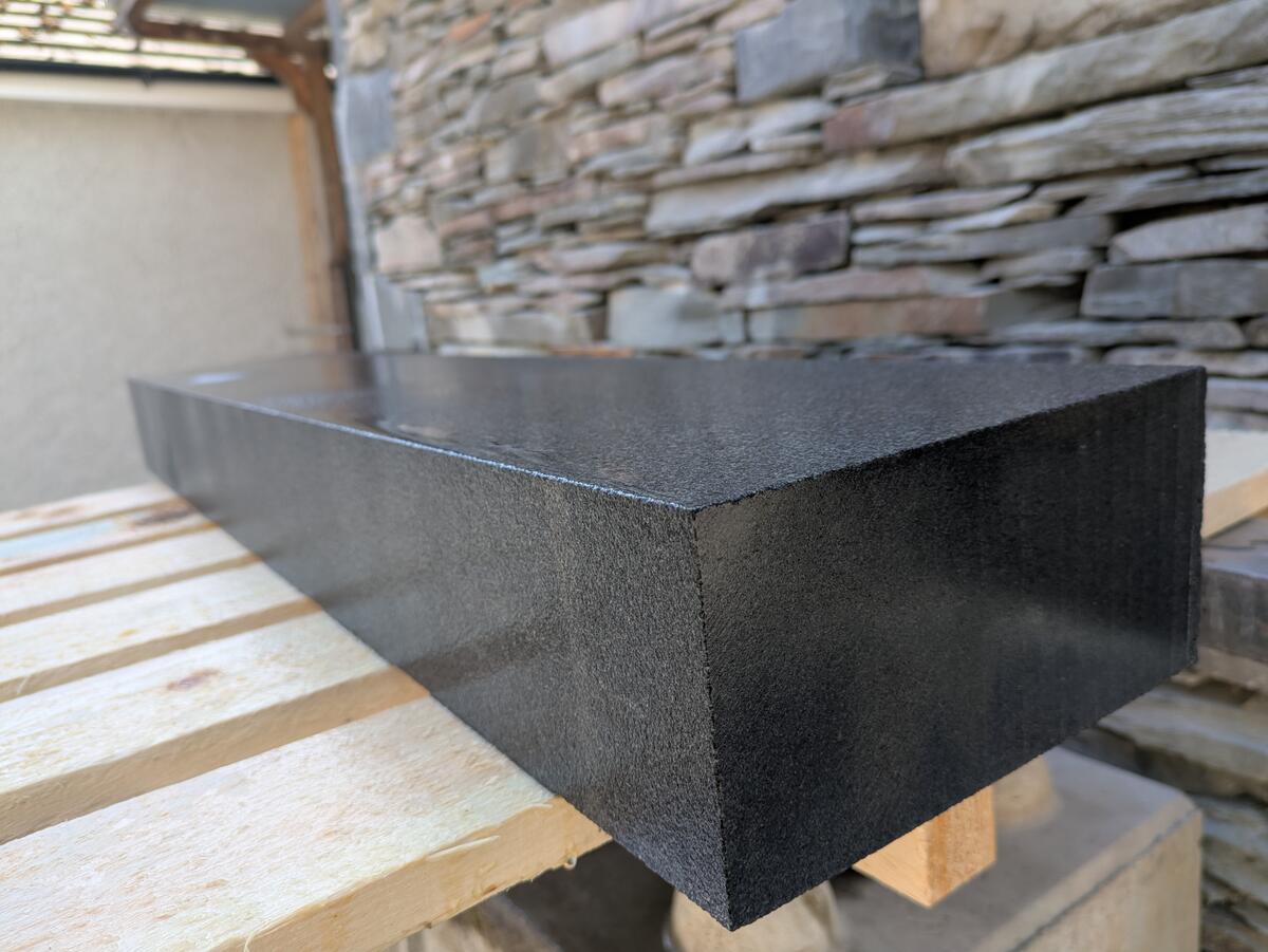 Black finished kerb wet displaying reflective qualities