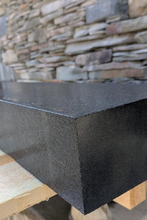 Black finished kerb wet displaying reflective qualities