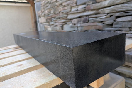 Black finished kerb wet displaying reflective qualities