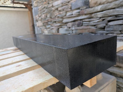 Black finished kerb wet displaying reflective qualities