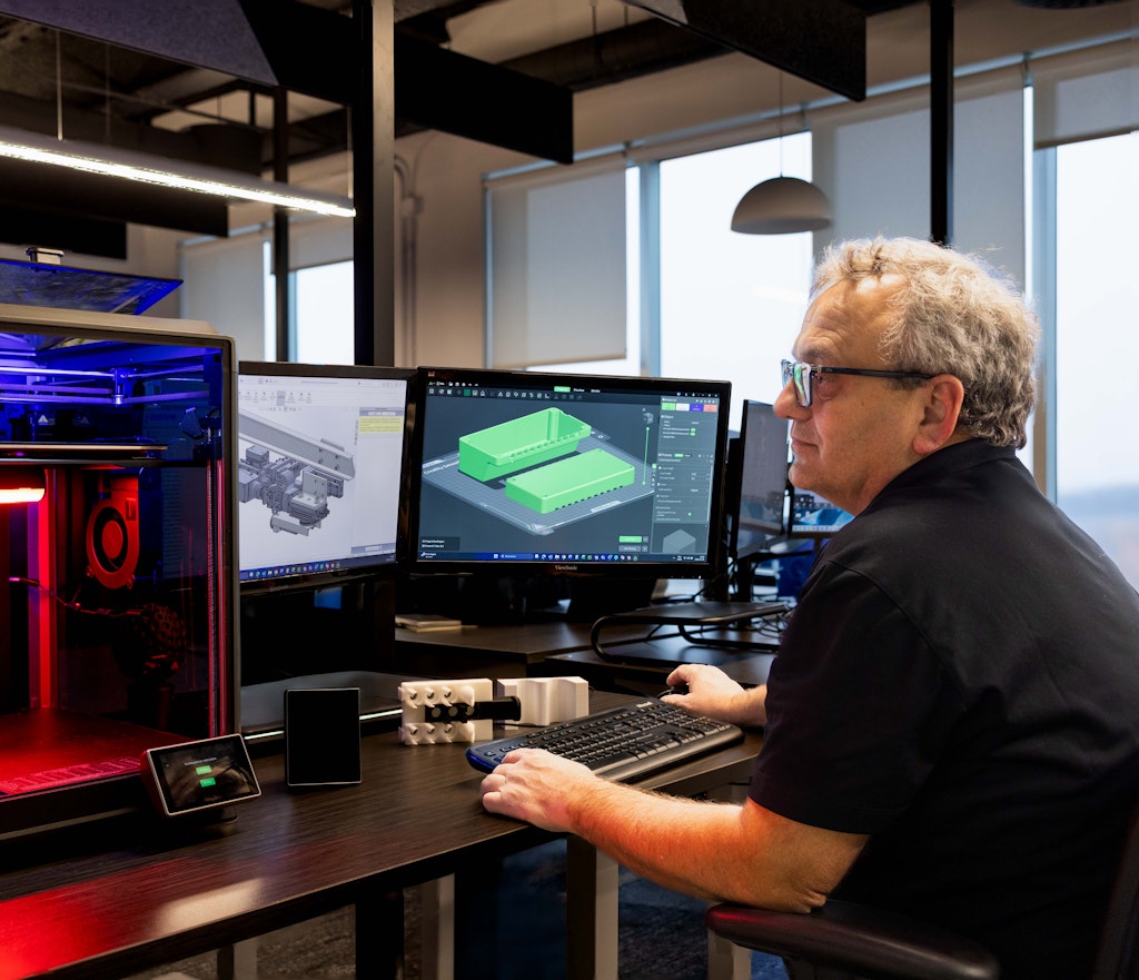 Homme devant une simulation 3D numérique d'un produit et devant un modélisateur de prototype