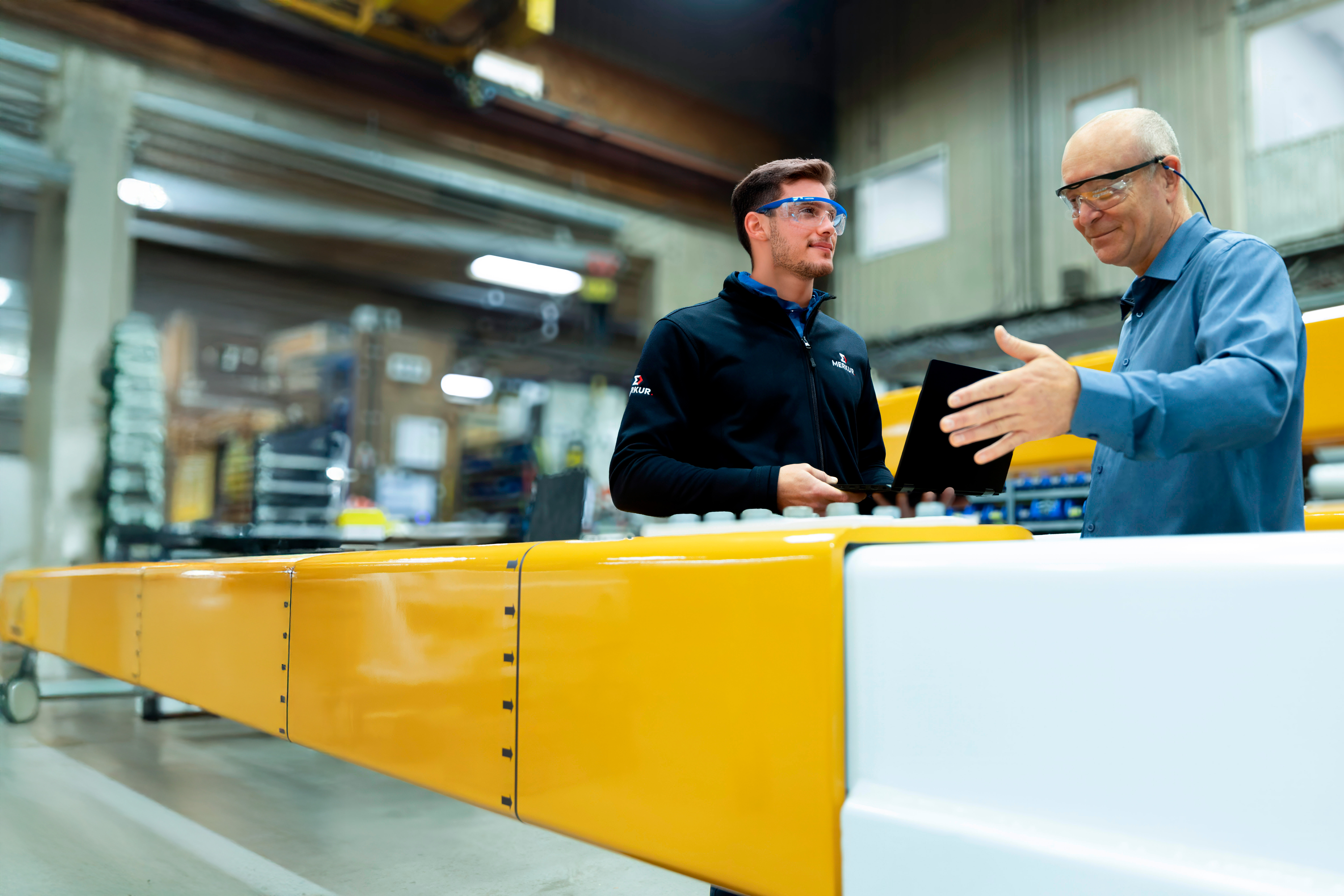 Deux hommes discutent devant des pièces d'acier
