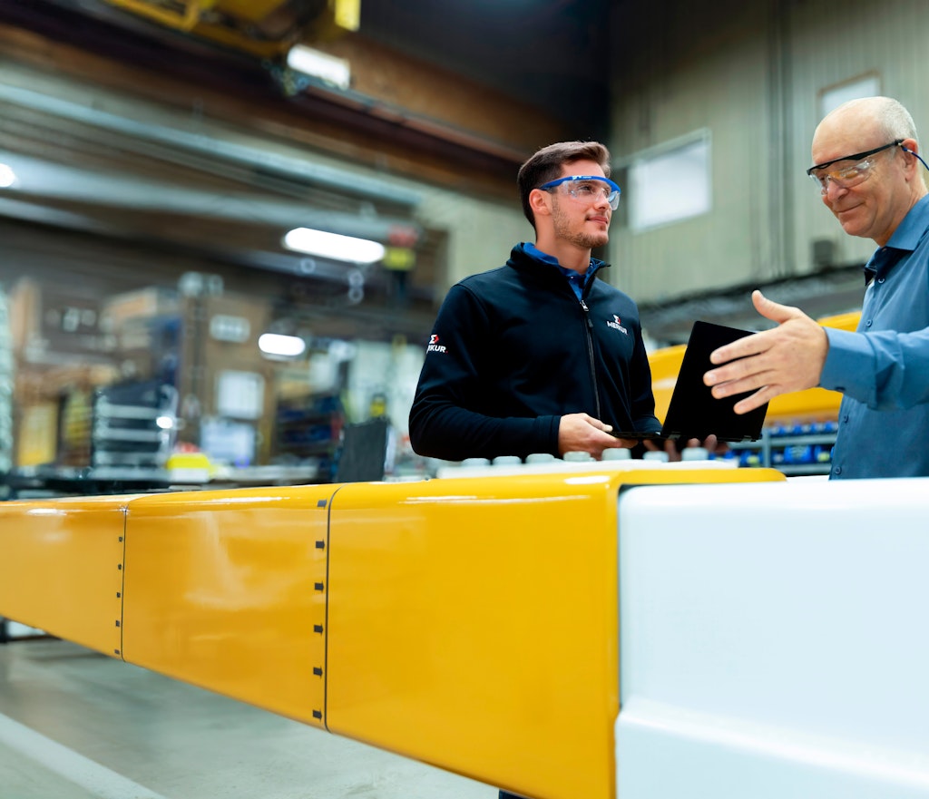 Deux hommes discutent devant des pièces d'acier