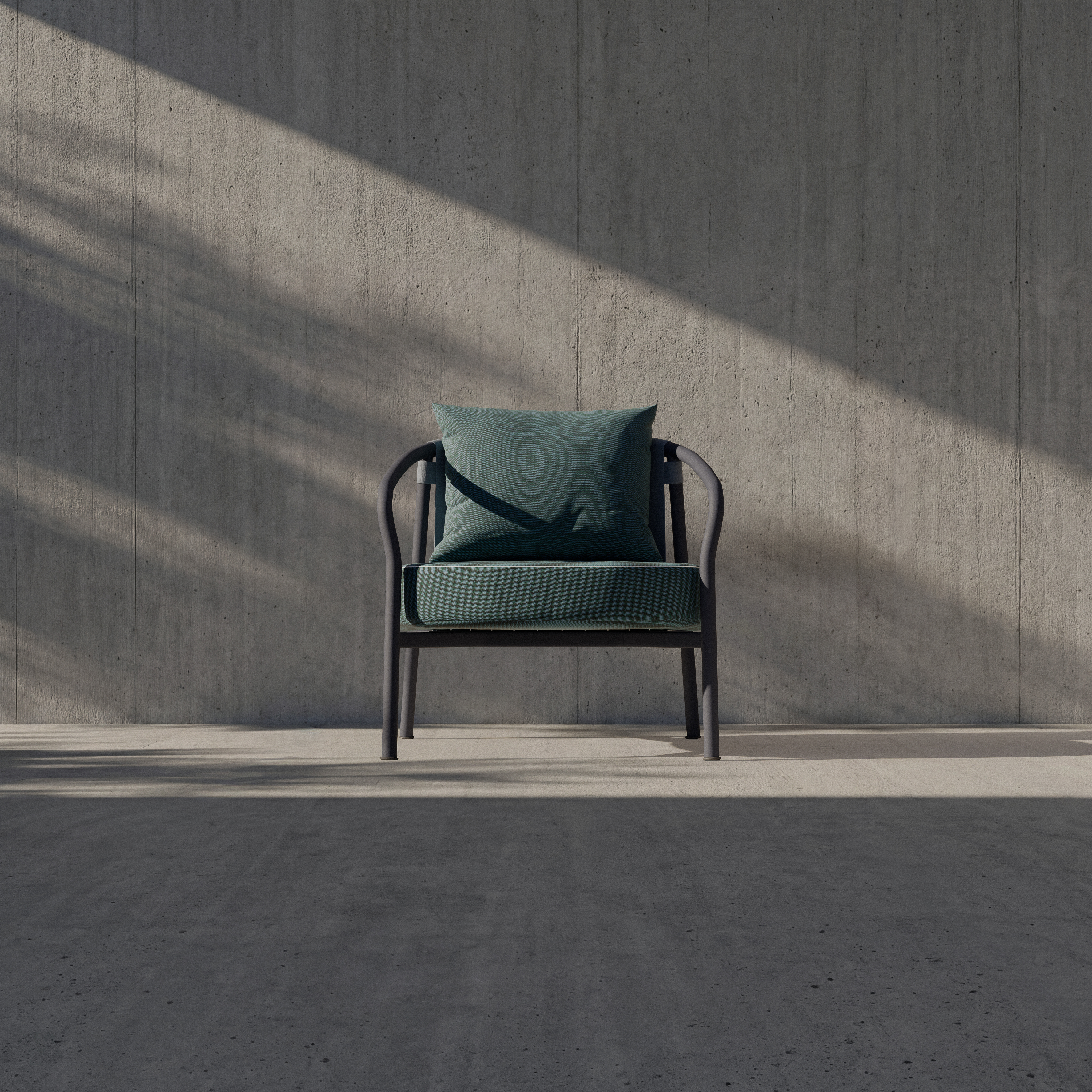 A modern green armchair with a matching cushion sits alone against a textured concrete wall. Sunlight casts diagonal shadows across the minimalist, empty space.