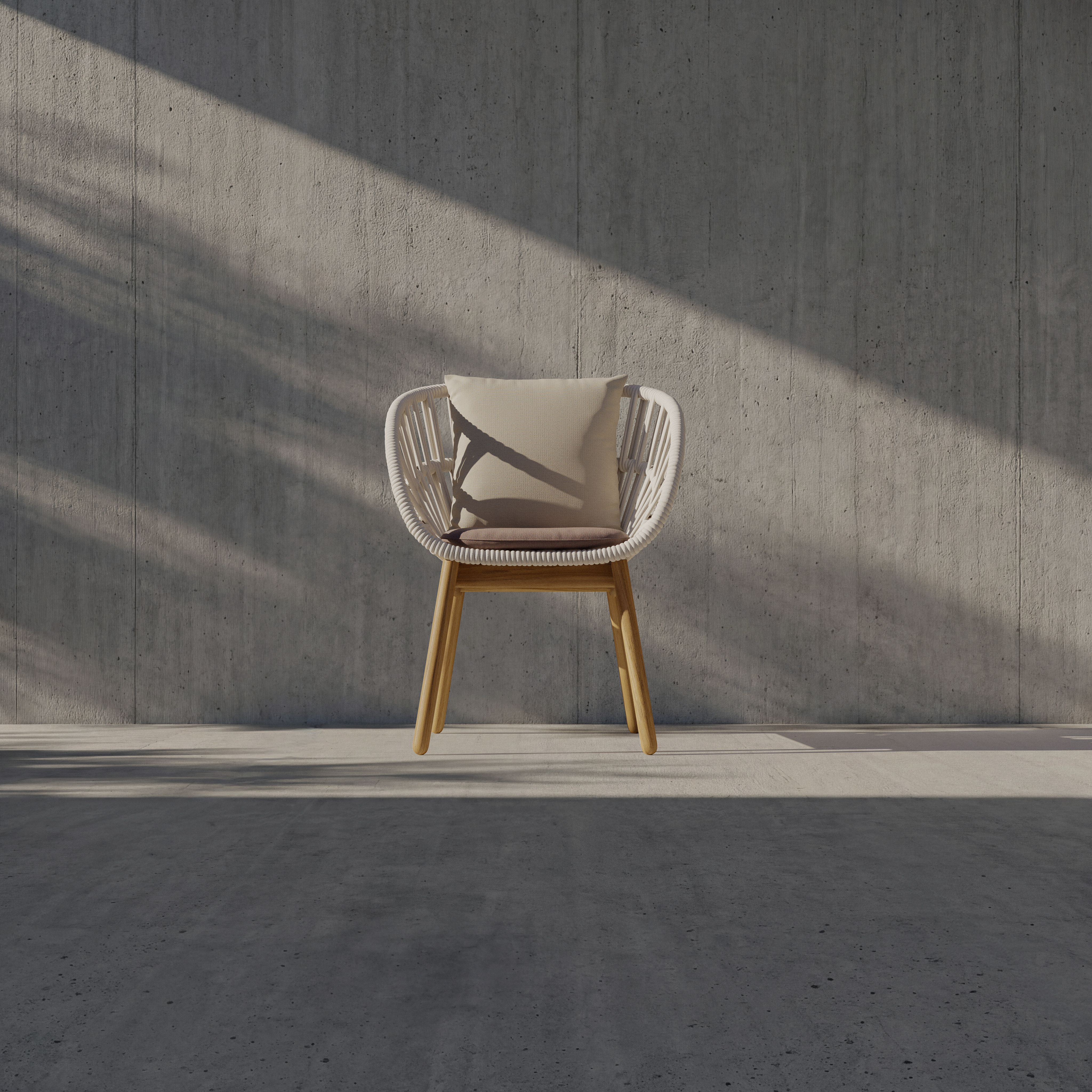A modern chair with a wooden frame and white woven seat, topped with a light-colored cushion, sits against a gray concrete wall with sunlight casting diagonal shadows across the scene.