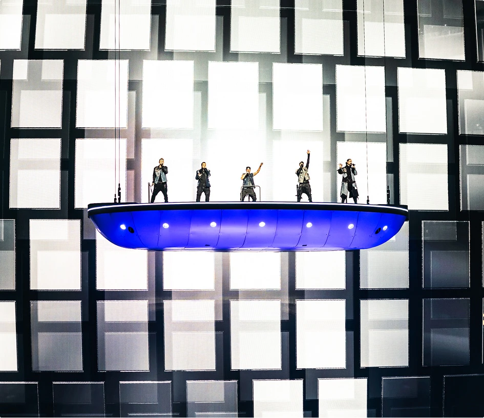 Backstreet Boys on flying stage, lit blue from below with layered square screen content behind them