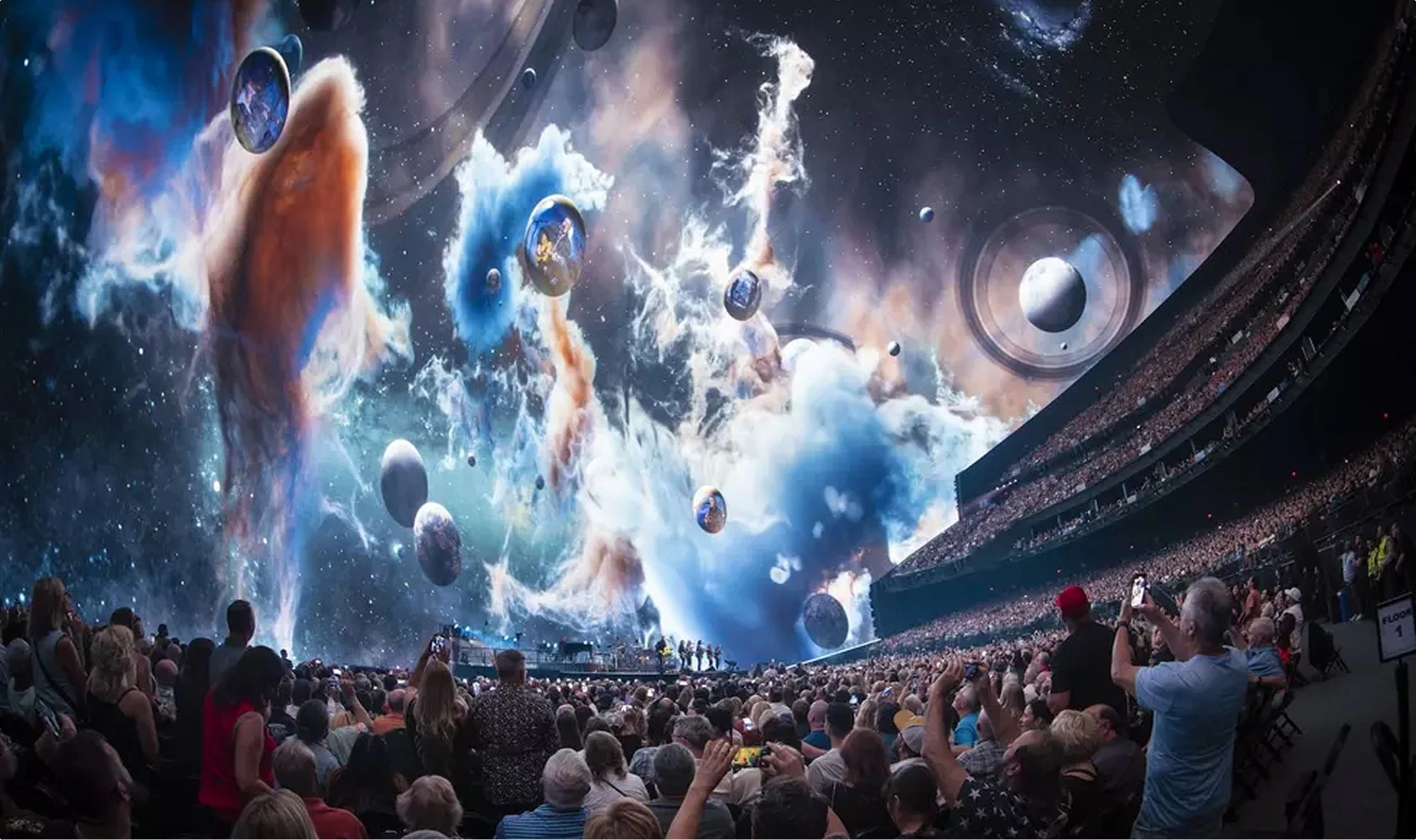 Space content blue orange clouds planets float on-screen at Sphere Las Vegas wide shot man in audience takes photo