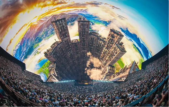 wide shot at Sphere Las Vegas audience in foreground, buildings grow in front of a moutainous sunset landscape