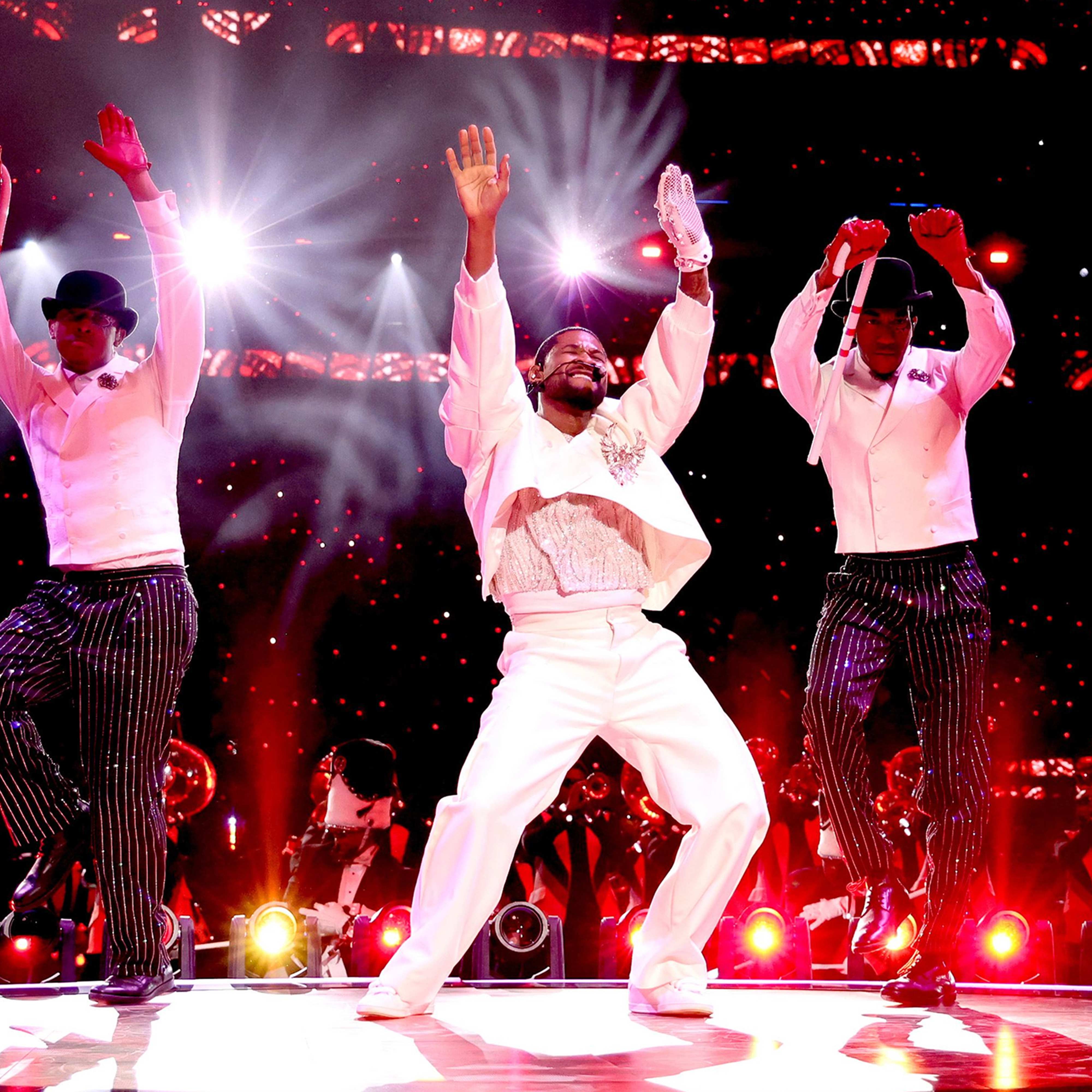 Usher and two dancers perform on-stage at the Super Bowl Halftime Show LVIII in white suits red lights
