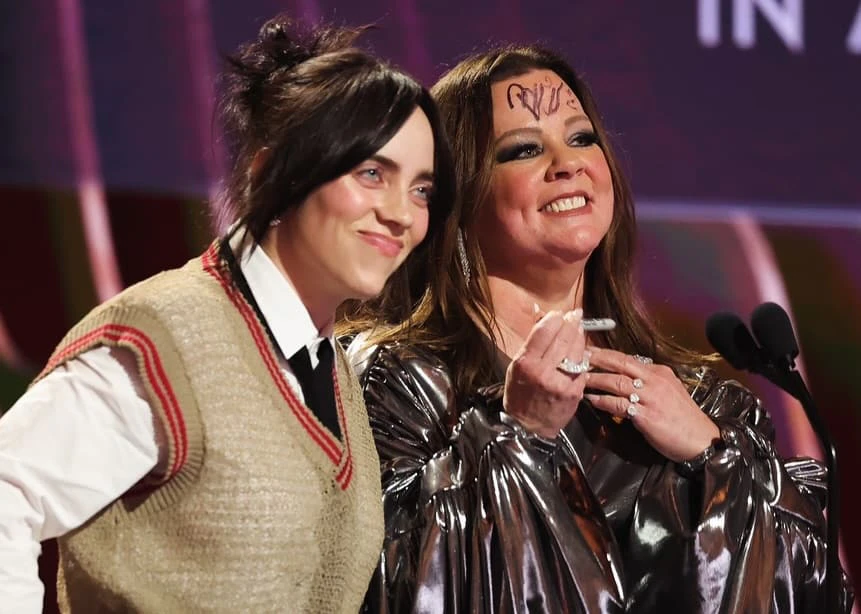 Billie Eilish and Melissa McCarthy present an award at the 30th Screen Actors Guild Awards. Billie Eilish autographs Melissa McCarthy's forehead with a marker.