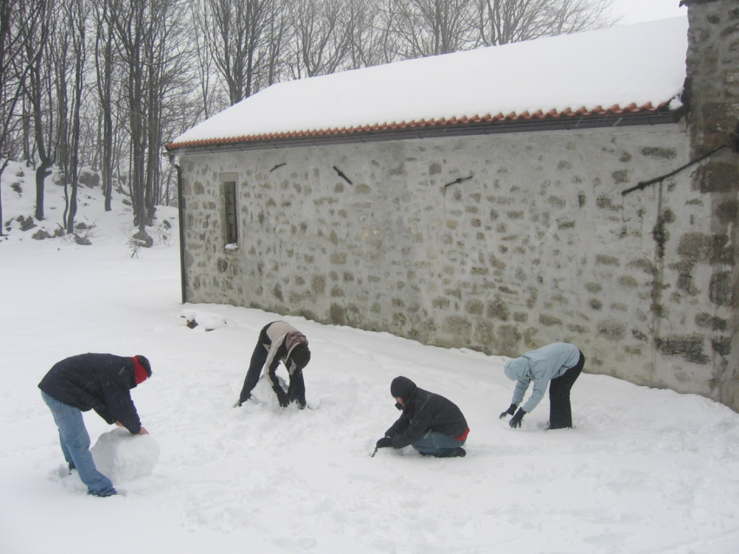 Skavti pri izdelovanju snežaka, v ozadju cerkev sv Lovrenca