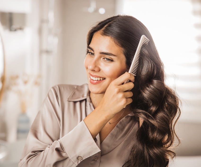 Woman smiline while brushing hair