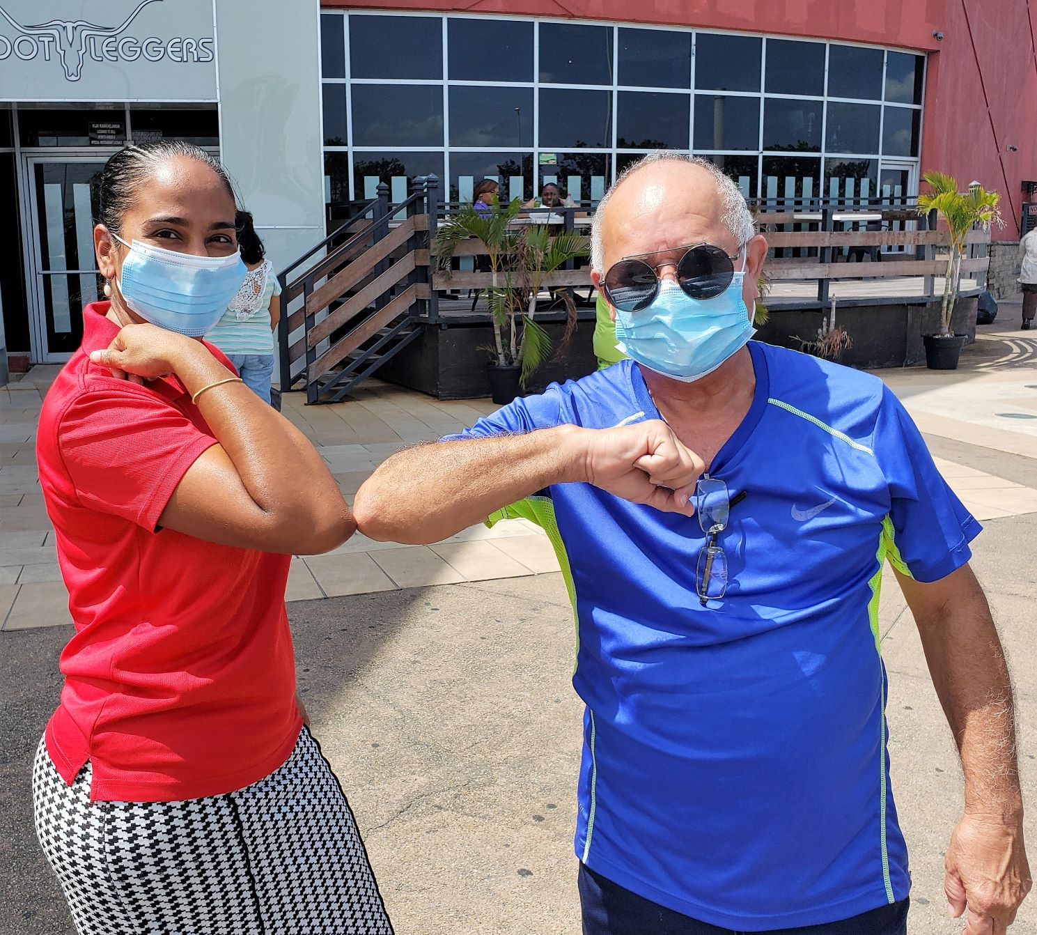 Two people wearing masks greeting each other