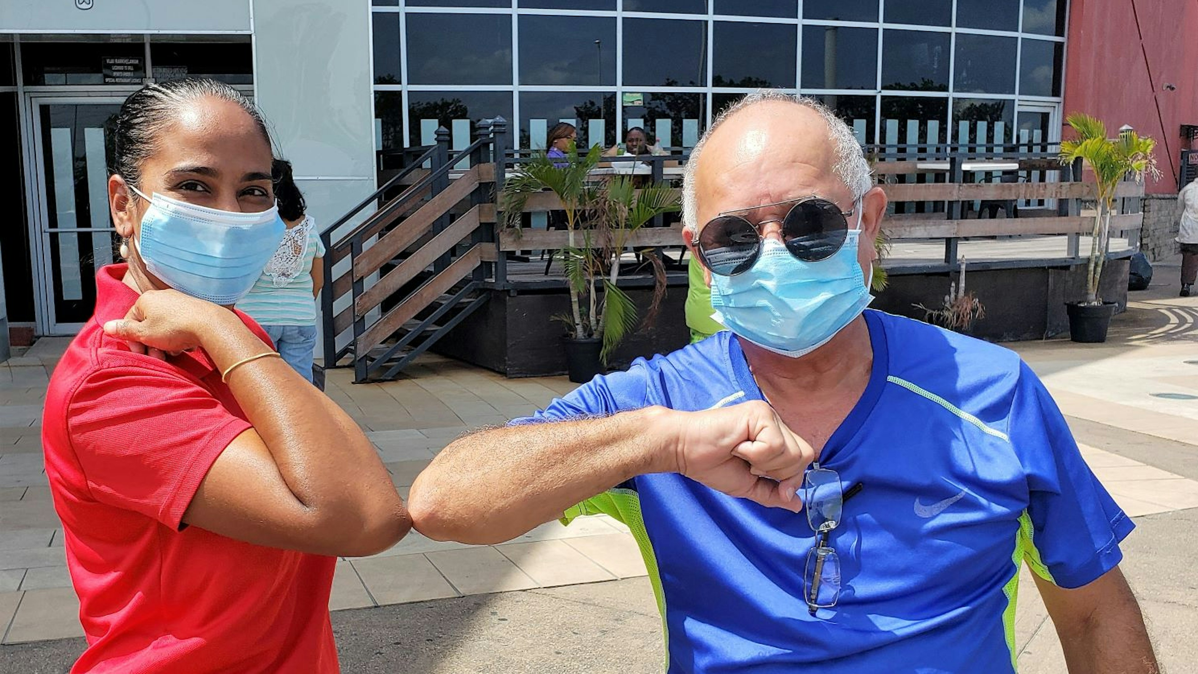 Two people wearing masks greeting each other