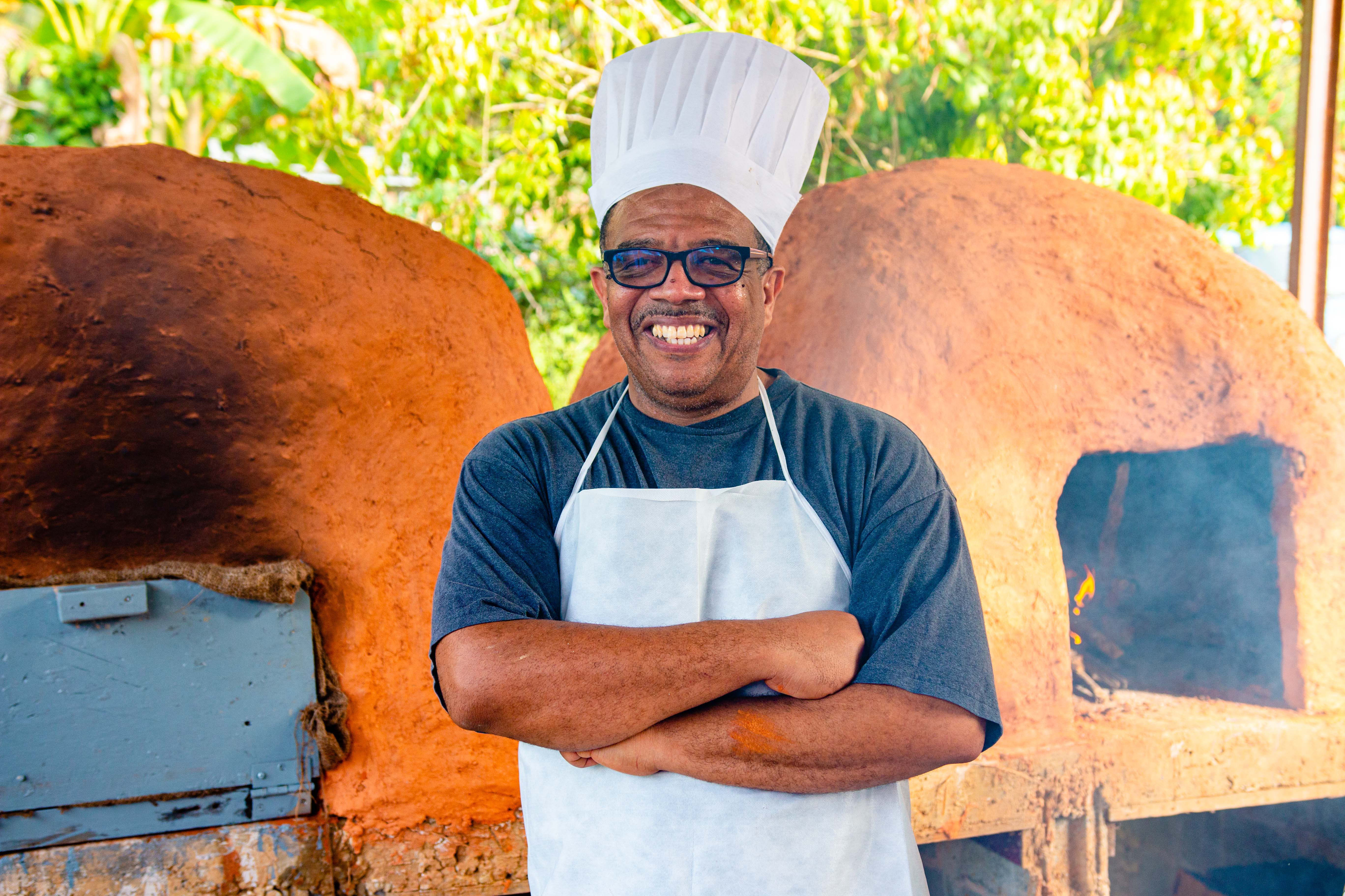 Baker standing infront dirt oven