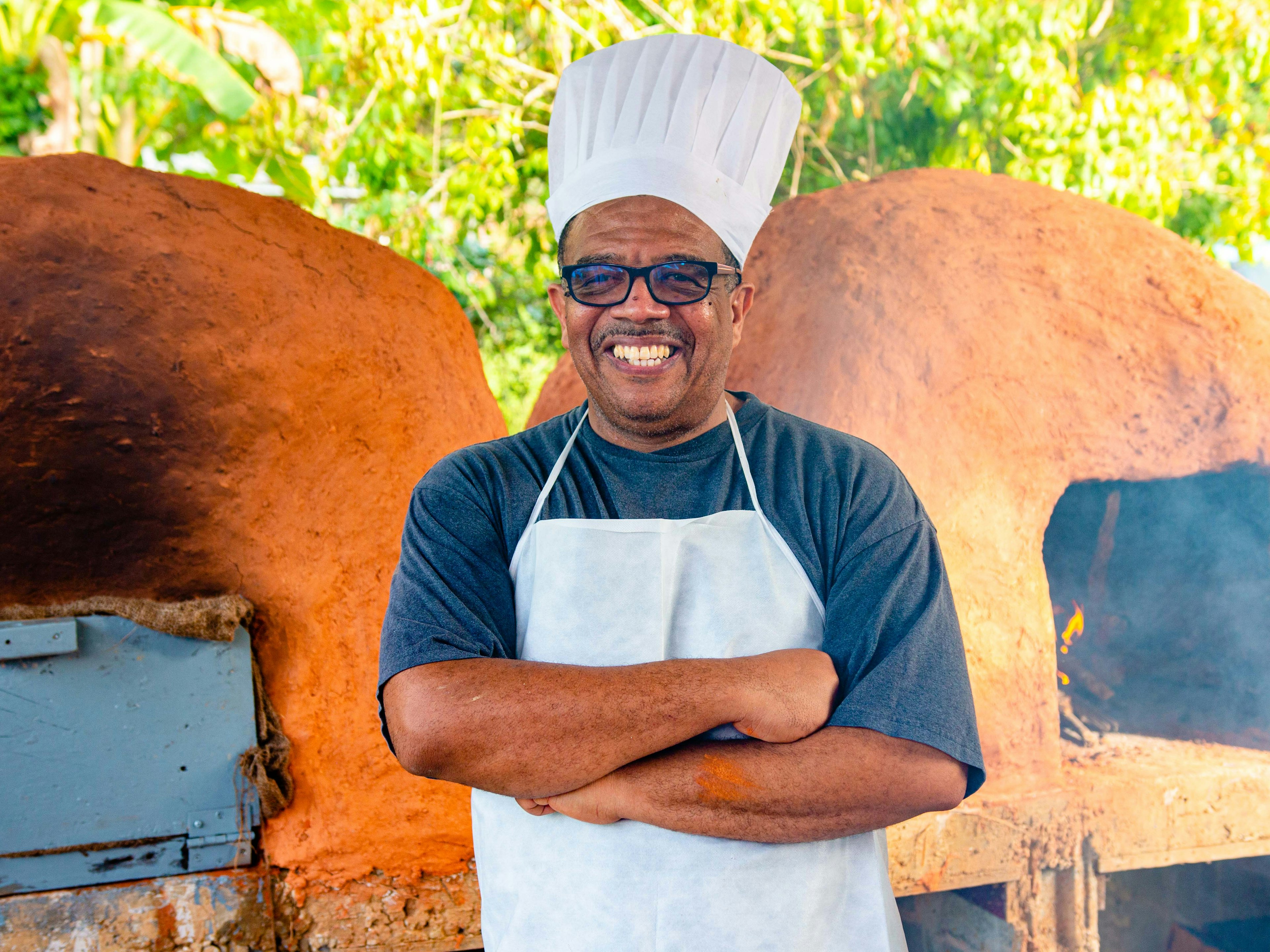 Baker standing infront dirt oven