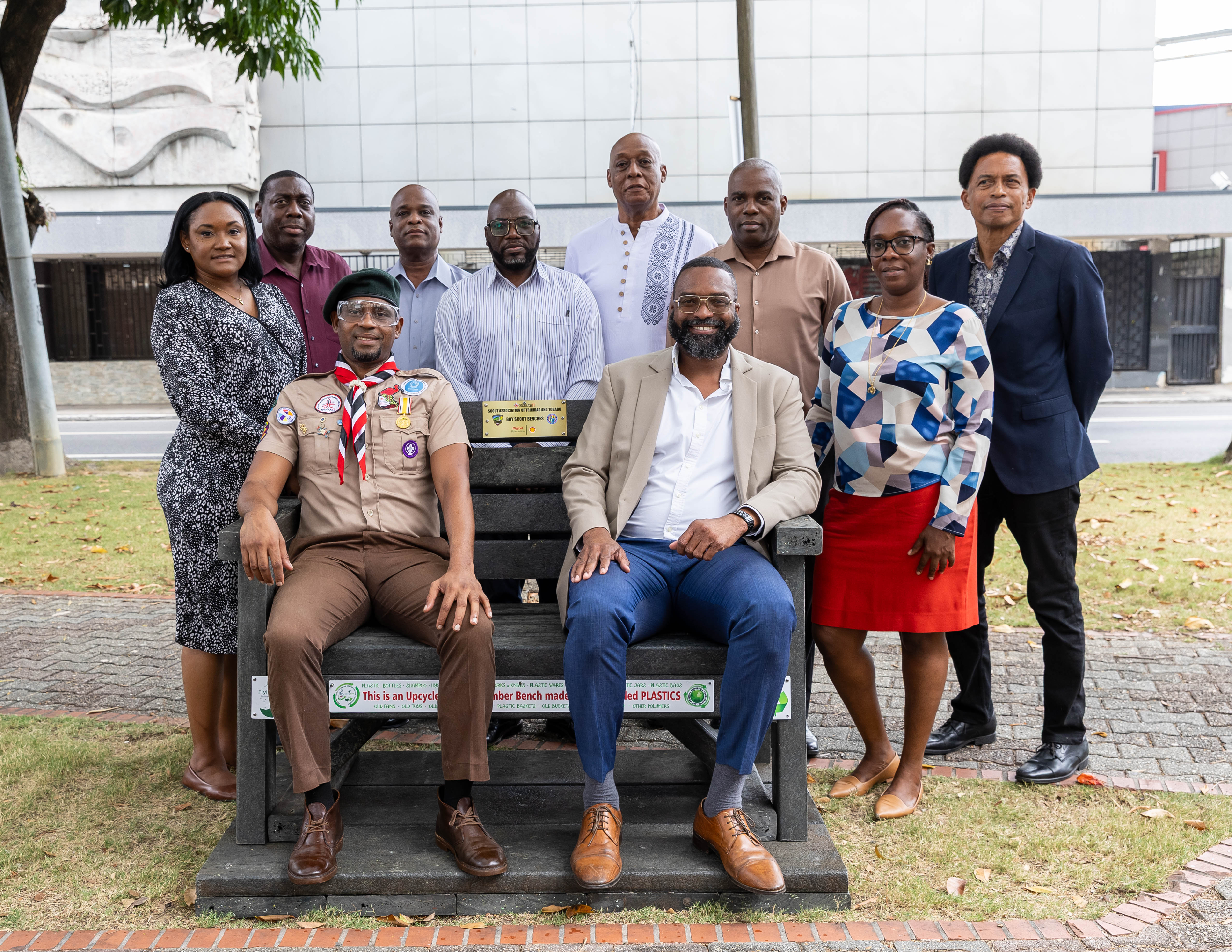 Scout leader and Mayor of PoS sit on upcycled bench