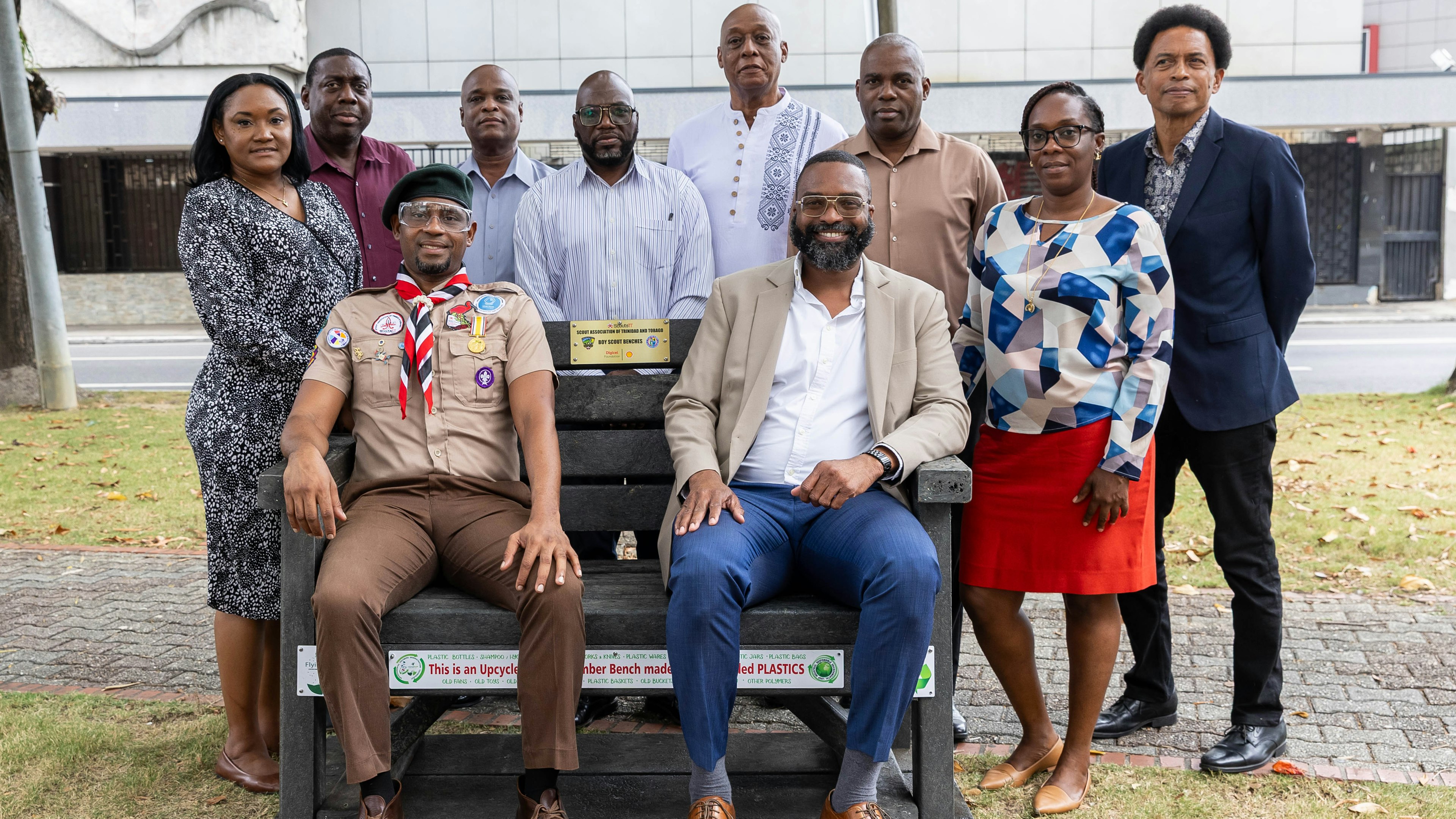 Scout leader and Mayor of PoS sit on upcycled bench