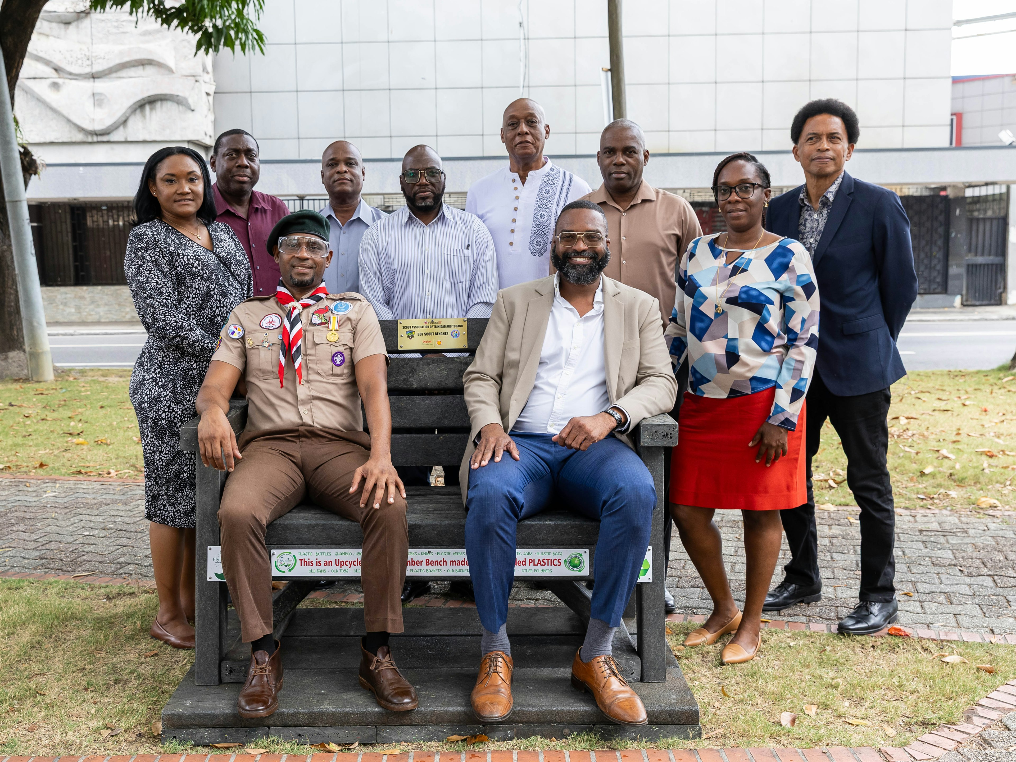 Scout leader and Mayor of PoS sit on upcycled bench