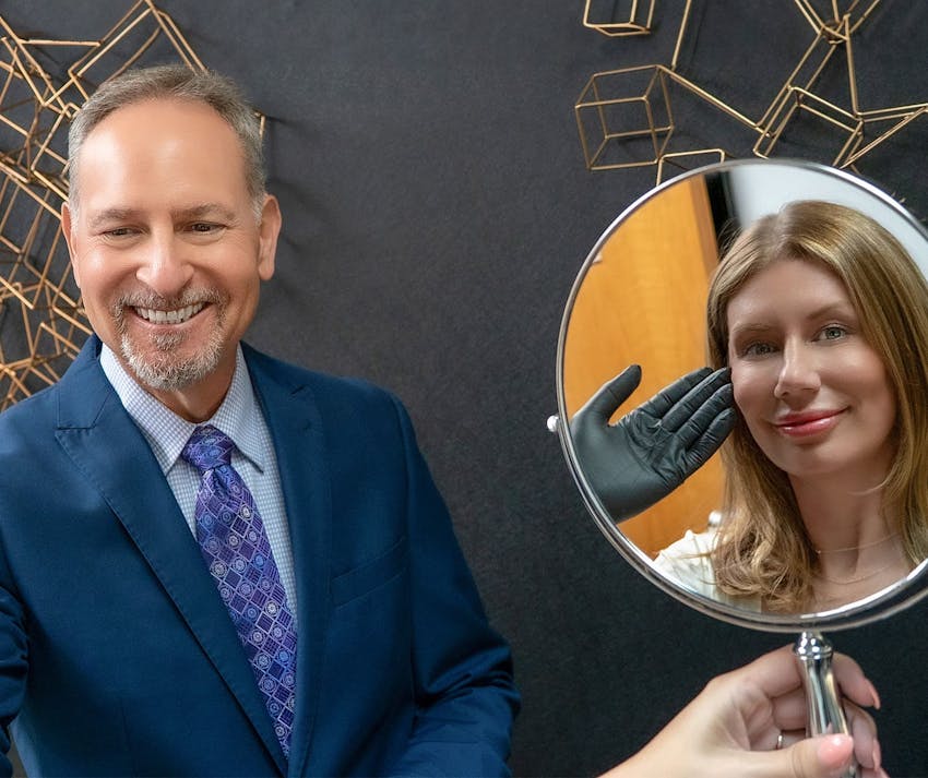 Dr. Berkowitz smiling at patient while she looks at mirror