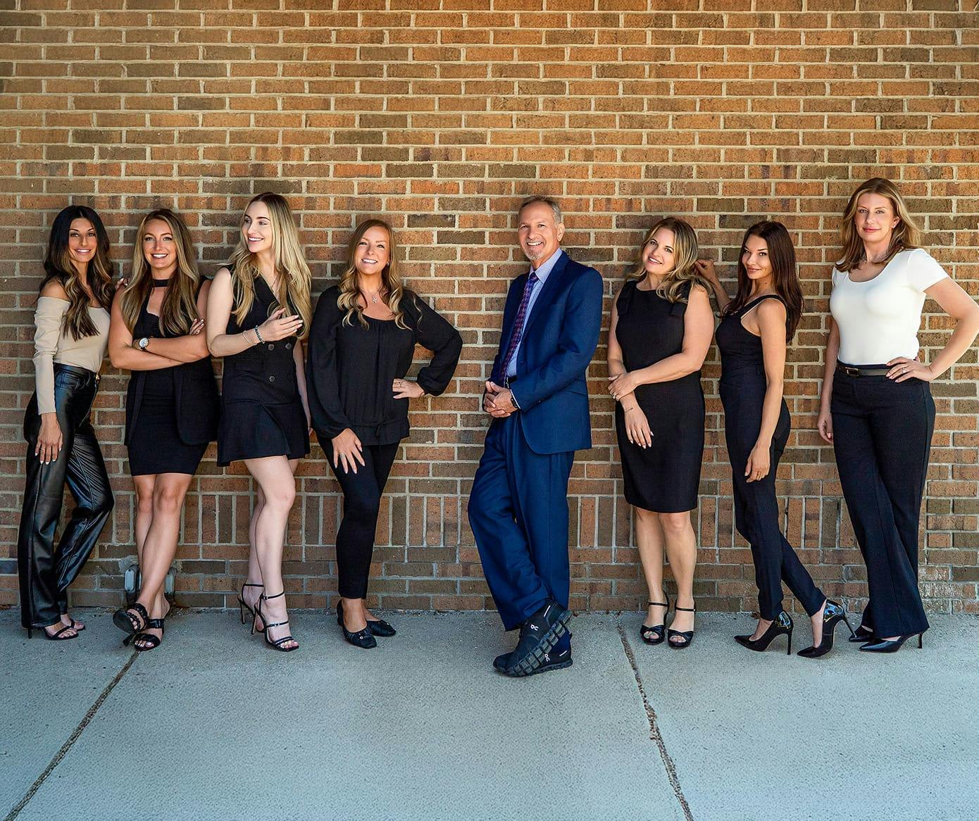 Dr. Berkowitz and his staff leaning against brick wall