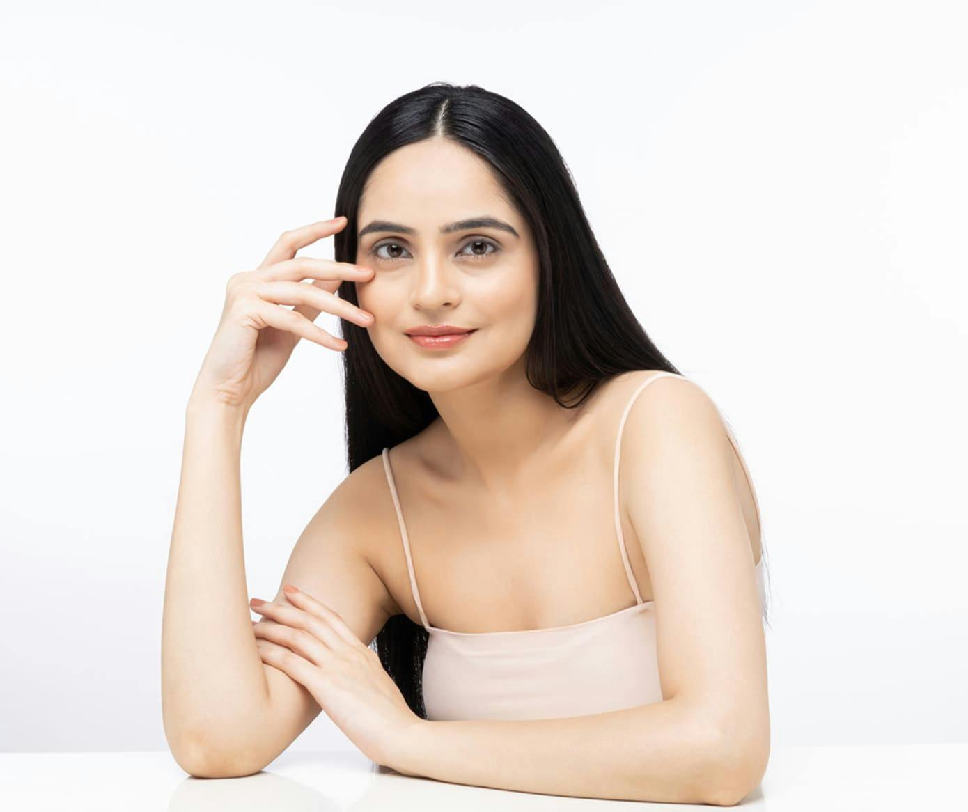 woman with long black hair with her hands near her face