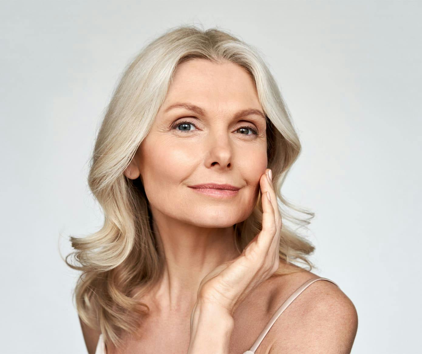 older woman grinning while touching her cheek with her hand