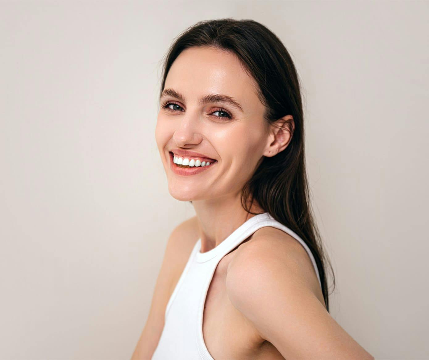 woman smiling while wearing a white tanktop