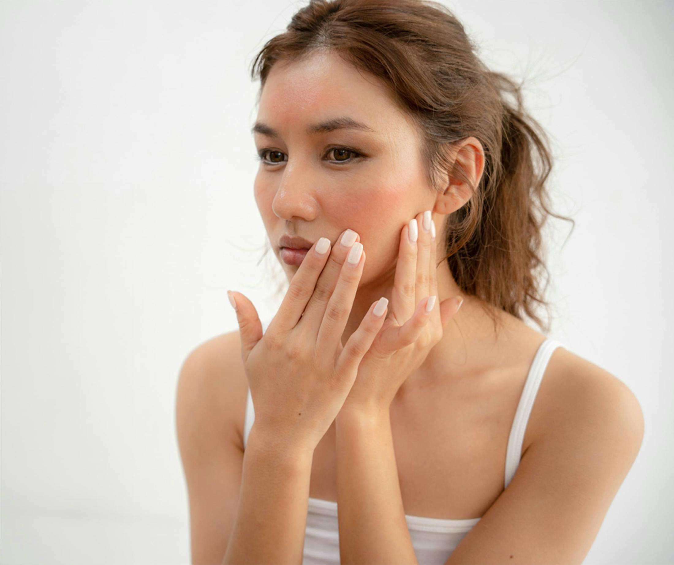 woman looking at her own cheek in the mirror