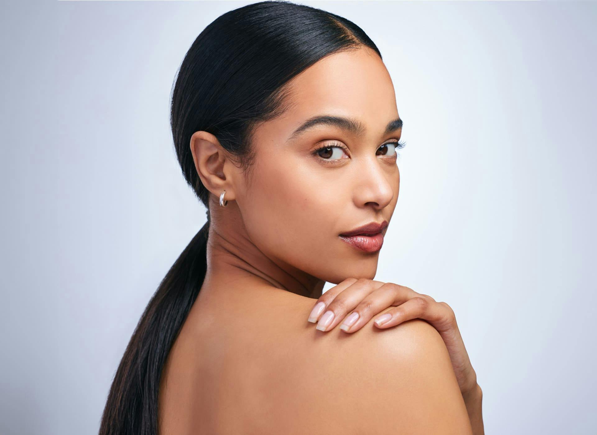 woman looking over her shoulder while her hand is resting on the same shoulder