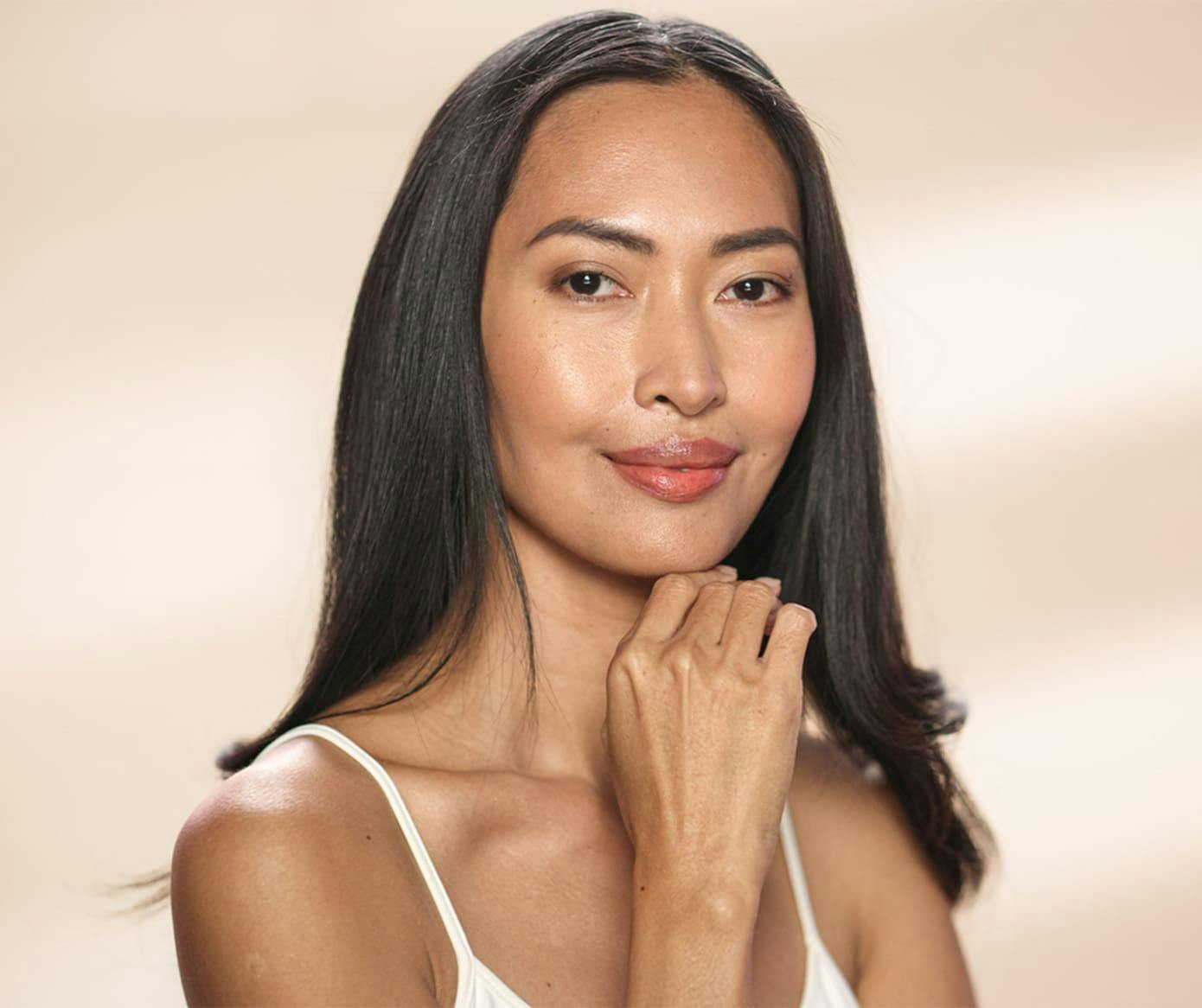 woman smiling with black hair and her hand under her chin