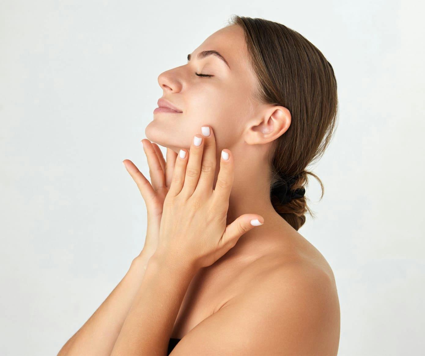woman with her hair in a low bun and her hands on her neck
