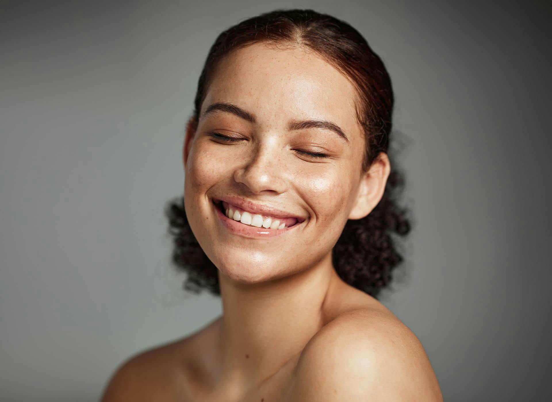 woman smiling with her eyes closed with her hair in a curly bun