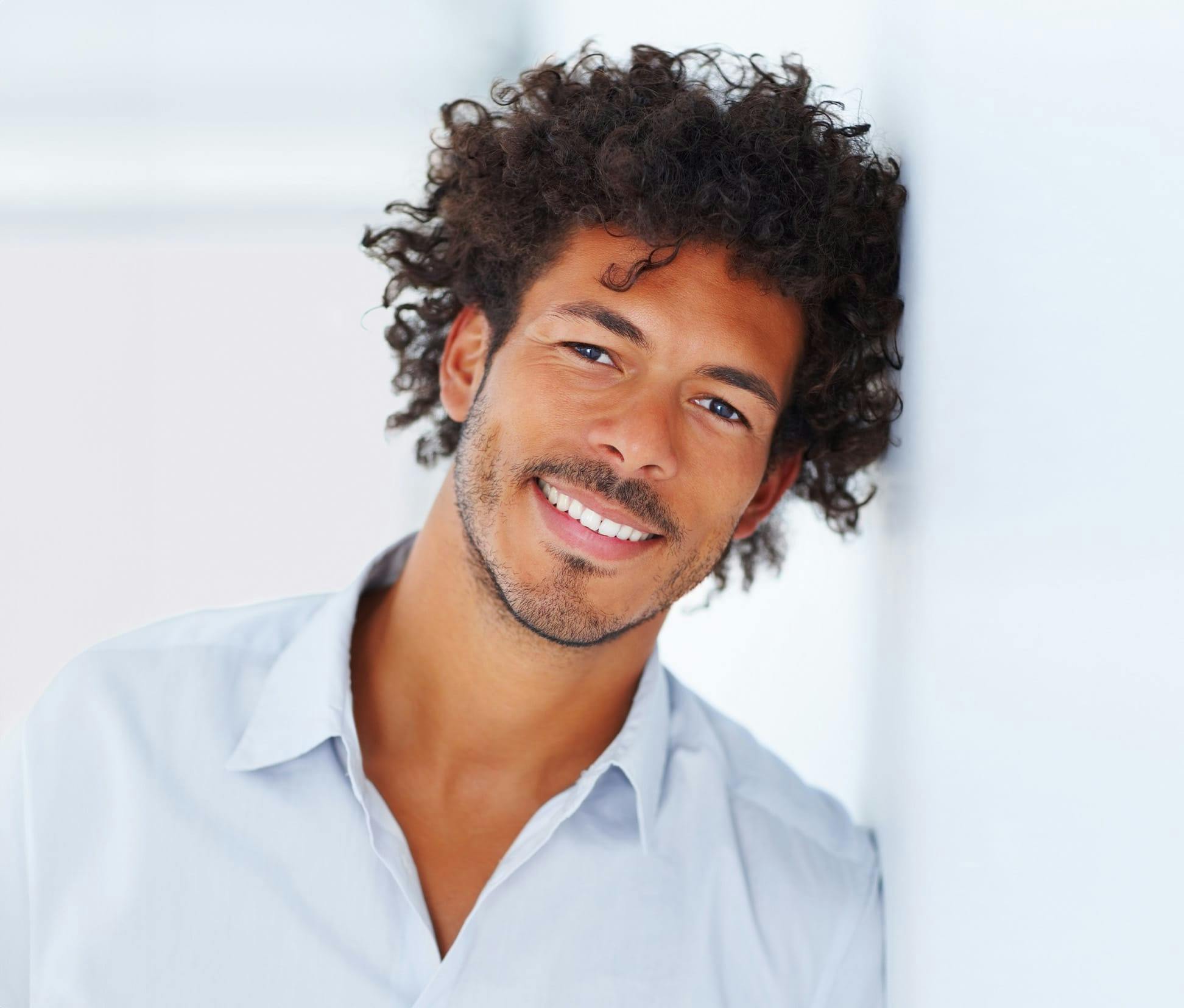 man with curly hair leaning against wall