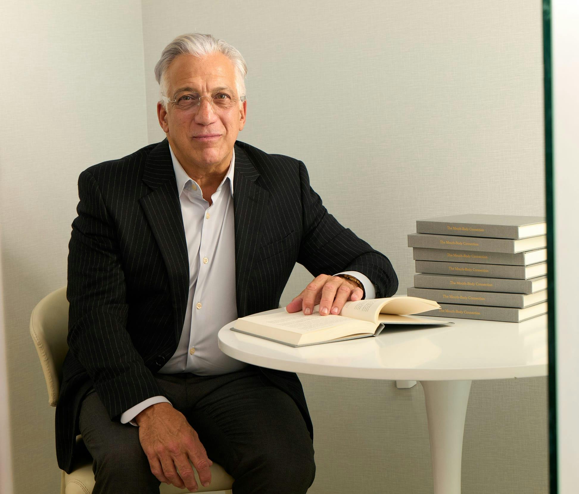 Gerry sitting in chair with suit on reading a book