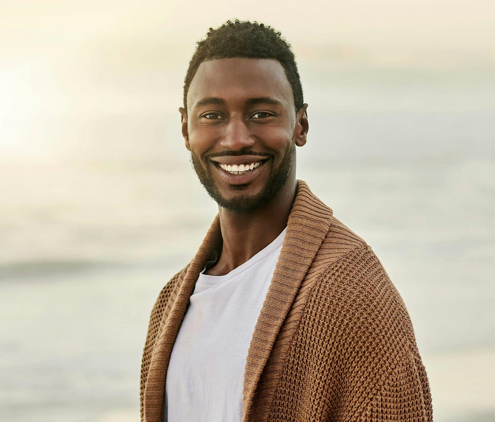man on beach with brown cardigan on