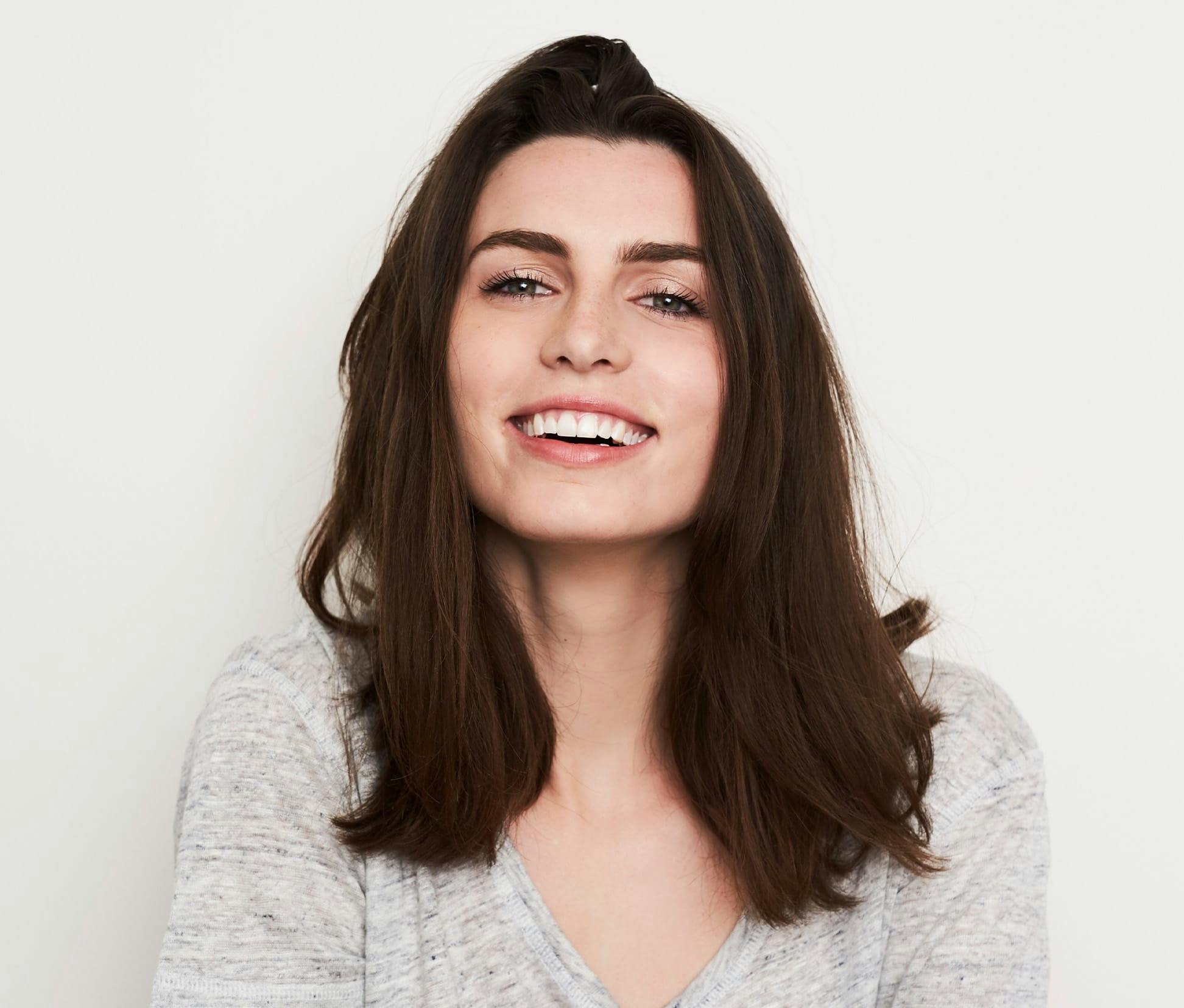 brunette woman smiling in grey shirt