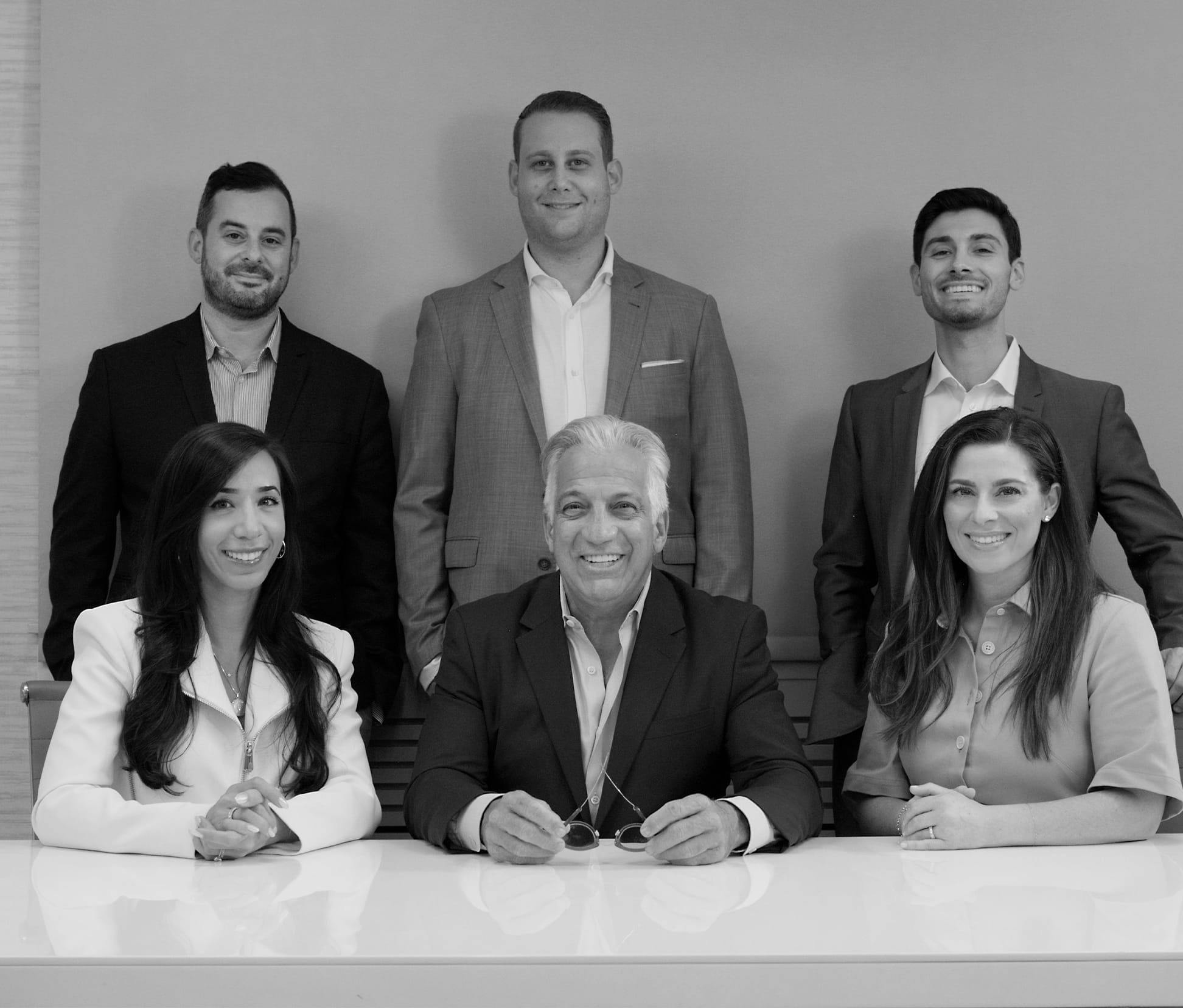 greyscale of 6 people in professional attire sitting and standing