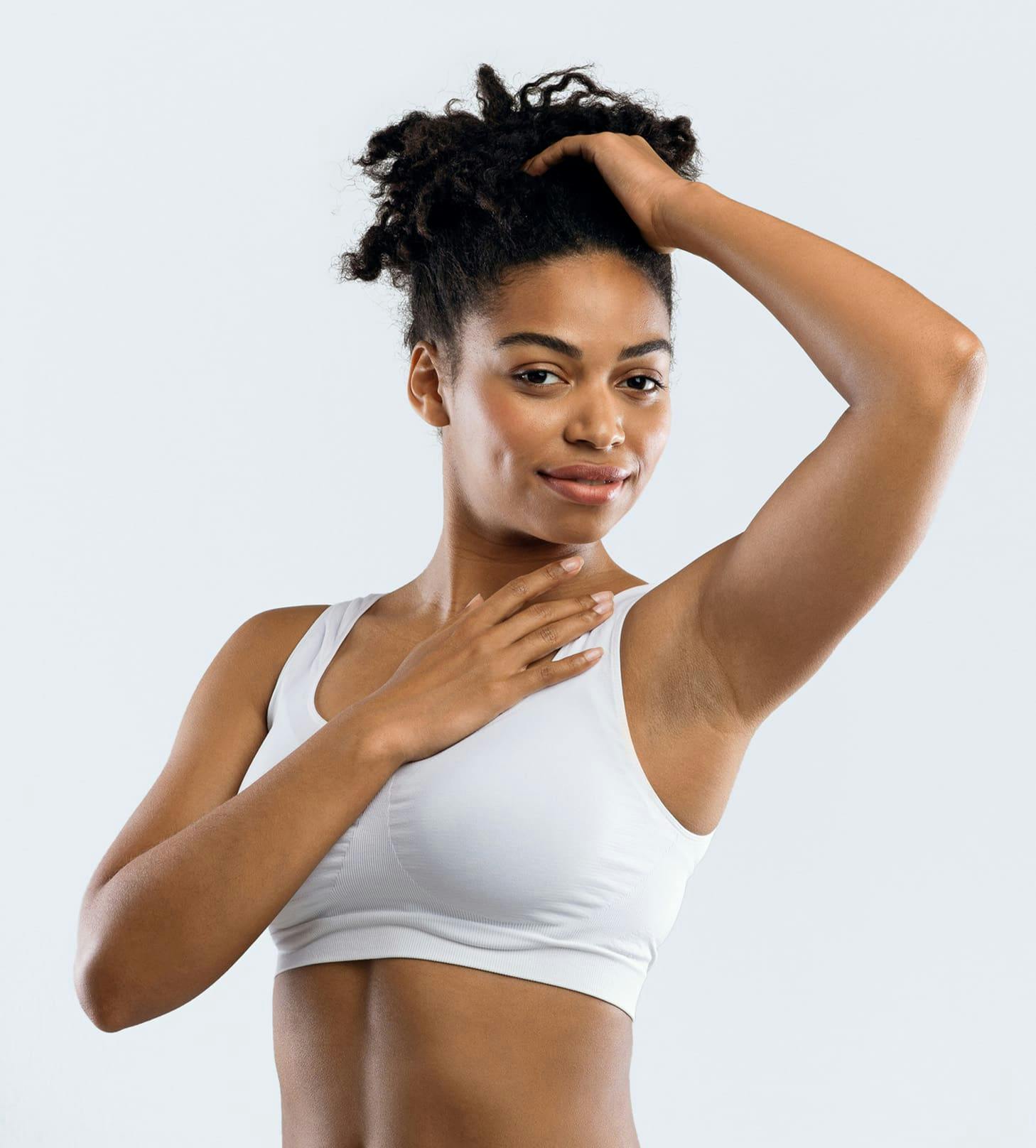 woman touching her hair and her neck in white sports bra