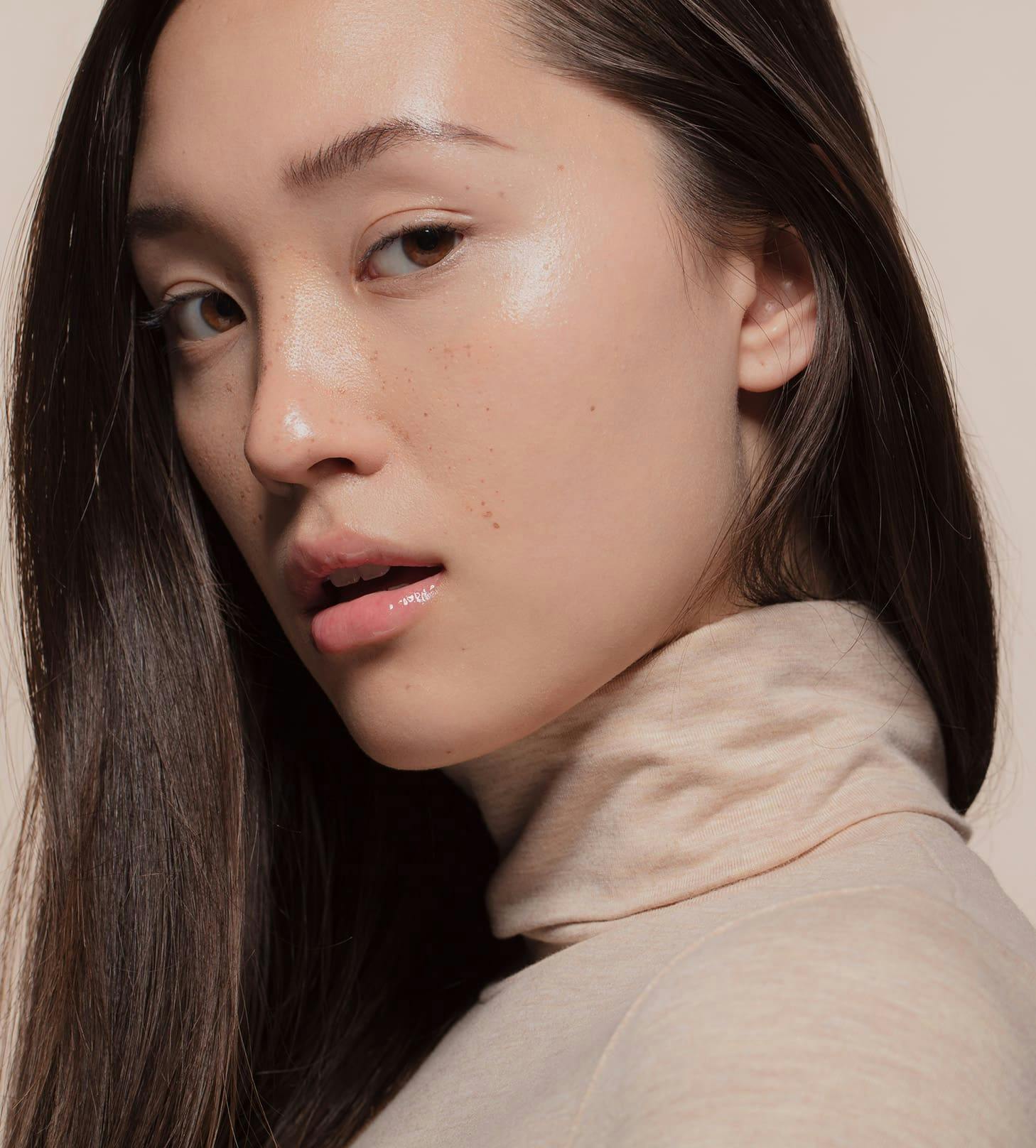 woman with straight brunette hair in beige turtleneck