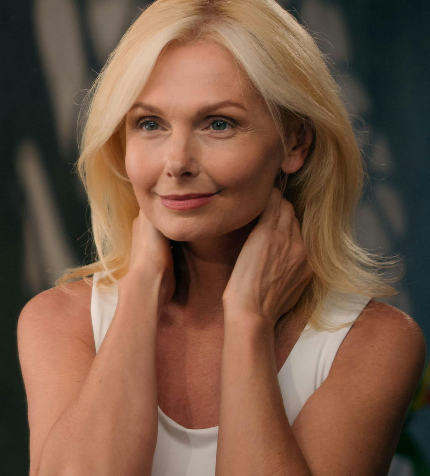 blonde woman with her hands near her neck