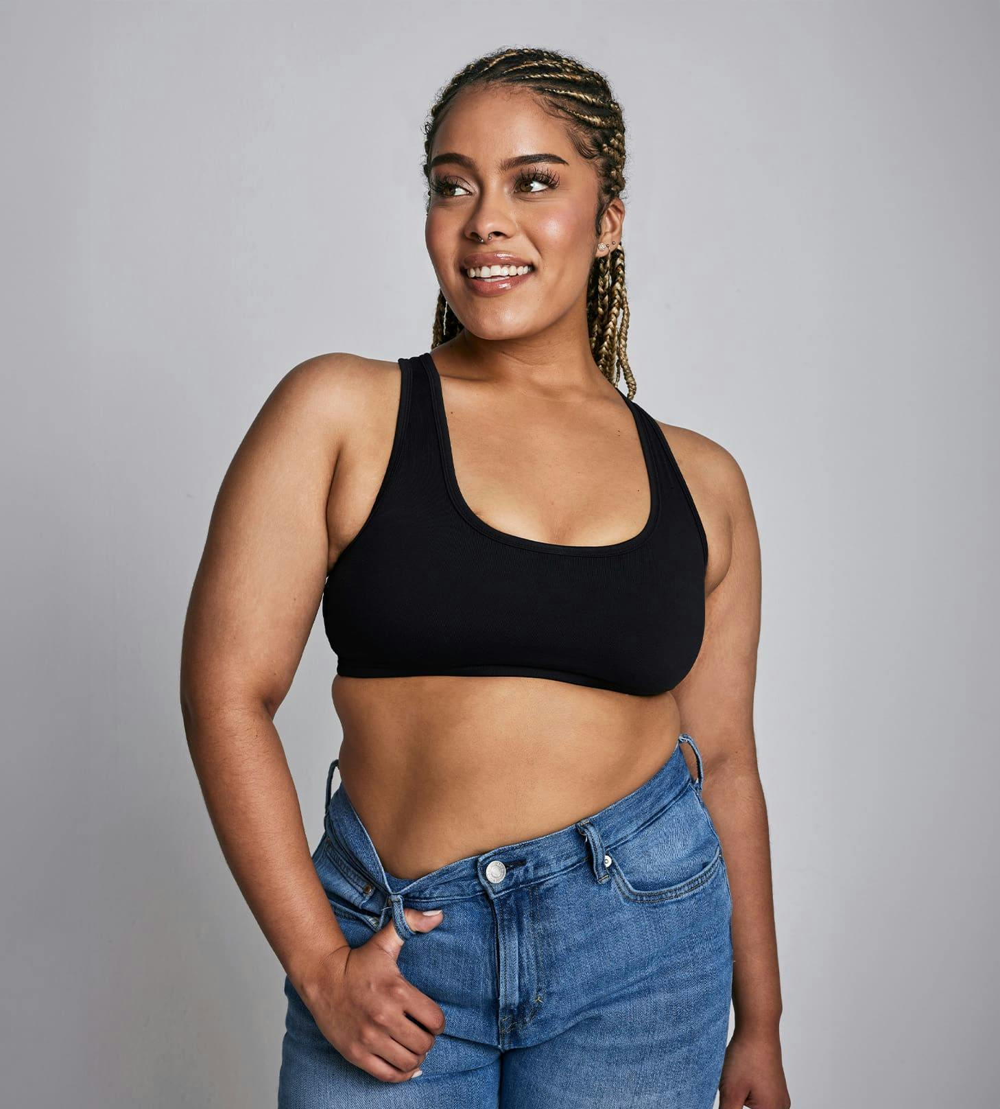 woman in jeans and a sports bra with her finger in the belt loop