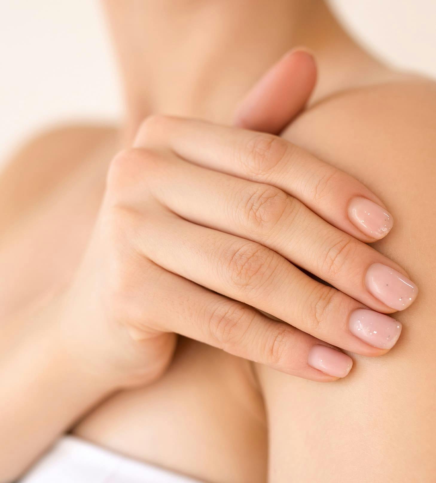 close up on woman's hand touching her shoulder