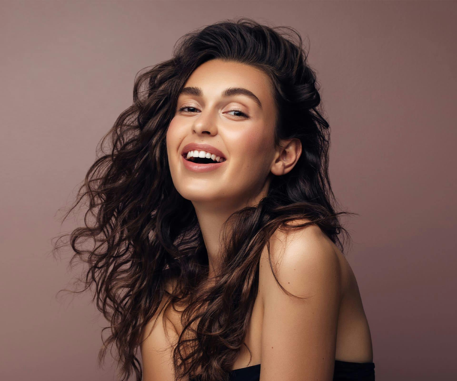 woman with wavy brunette hair smiling