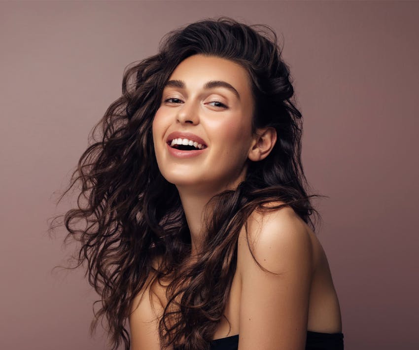 woman with wavy brunette hair smiling